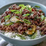 A close-up of a Korean Ground Beef Bowl, featuring savory ground beef, fluffy rice, and vibrant quick pickled vegetables topped with sesame seeds.