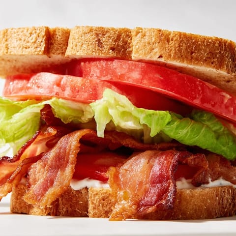 BLT Sandwich cut in half on a plate, showcasing stacked layers and crunchy textures.