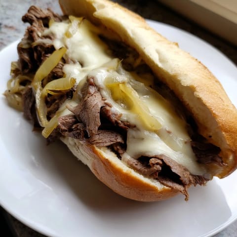 Classic Philly Cheesesteak sandwich loaded with tender ribeye, onions, and melted provolone on a toasted roll.