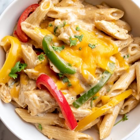A close-up view of tender chicken, onions, and pasta in a creamy, spicy sauce.