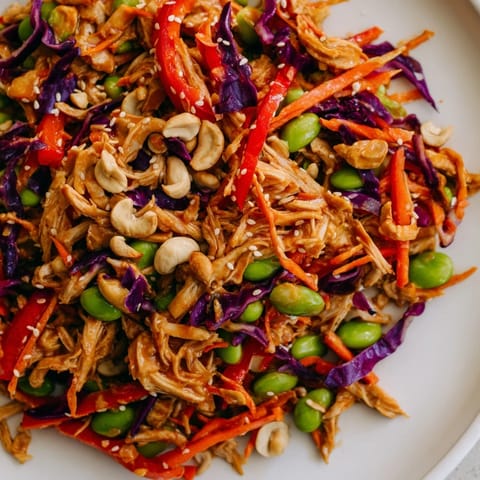 Edamame Crunch Chicken Salad served in a white bowl with colorful carrots, red bell peppers, and cashews for extra texture.  