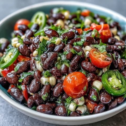 A bright bowl of Cowboy Caviar with black beans, corn, and peppers next to tortilla chips