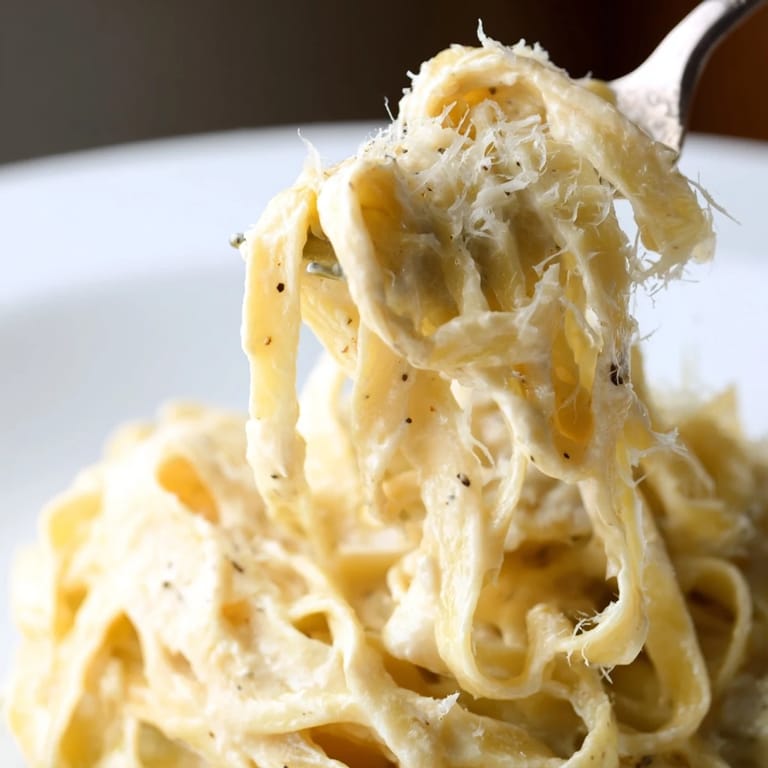 Roasted garlic cream pasta is a comforting Italian main dish served steaming hot, with melted Parmesan cheese and fresh herbs.