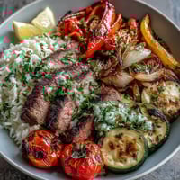 A colorful sheet pan steak and veggie bowl with juicy steak slices and roasted vegetables over fluffy rice.