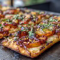 Grilled flatbread with peaches, Brie, and BBQ sauce—a smoky, sweet, and creamy summer appetizer.